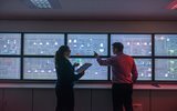 Man and Woman behind a wall of data screens