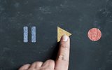 Finger pushing a yellow play button on chalk board
