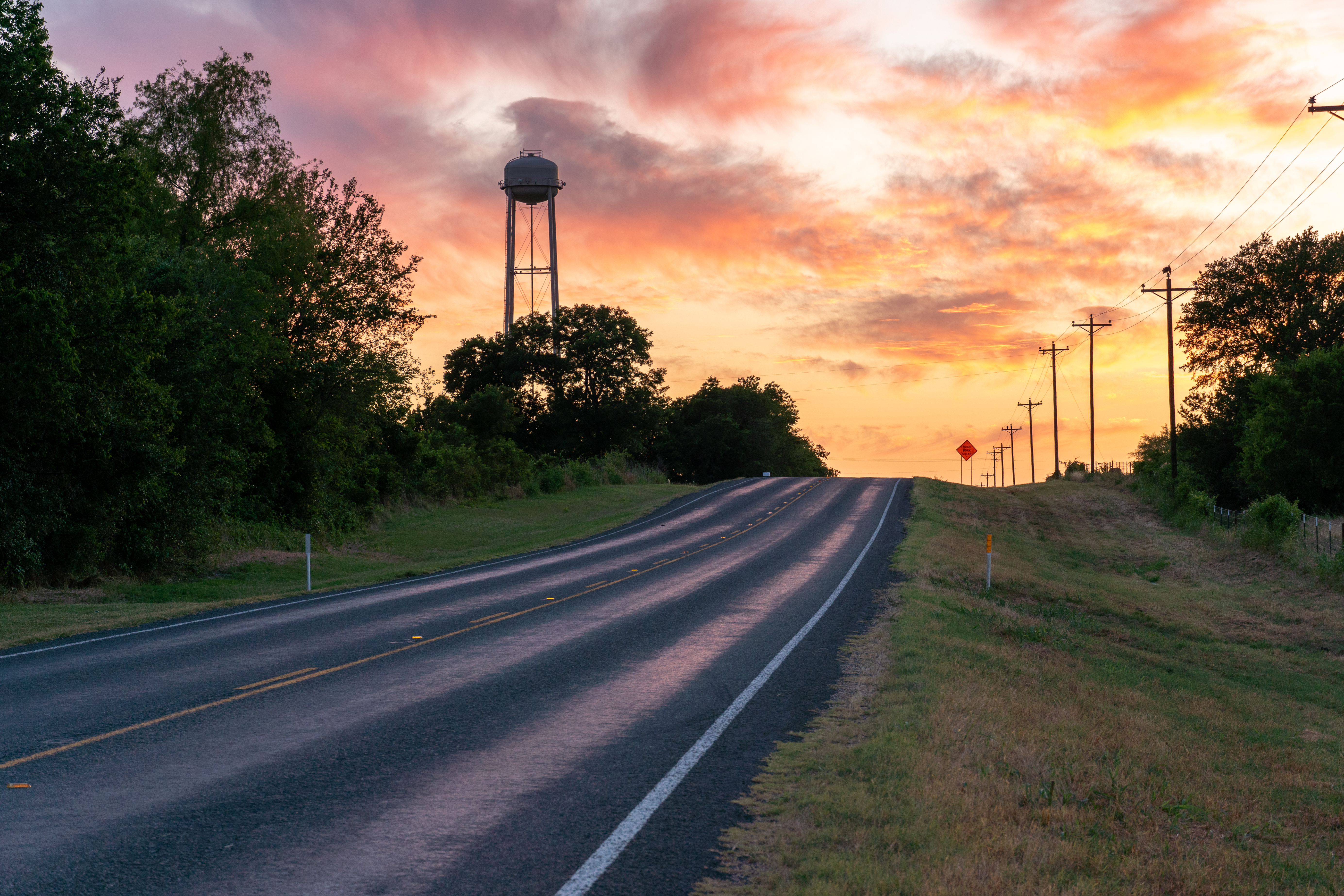 Country Texas road with sunset and water tower