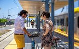 Man and woman on off bicycles near light rail